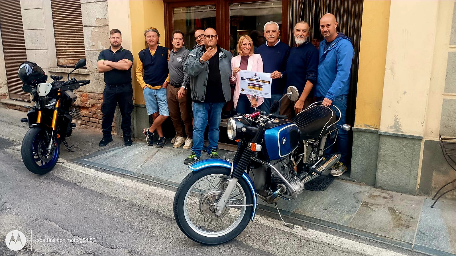 Consegna dell'attestato 'Comune Amico dei Motociclisti' CAM-0010 al Comune di Monale: amministratori e motociclisti davanti al municipio con due moto